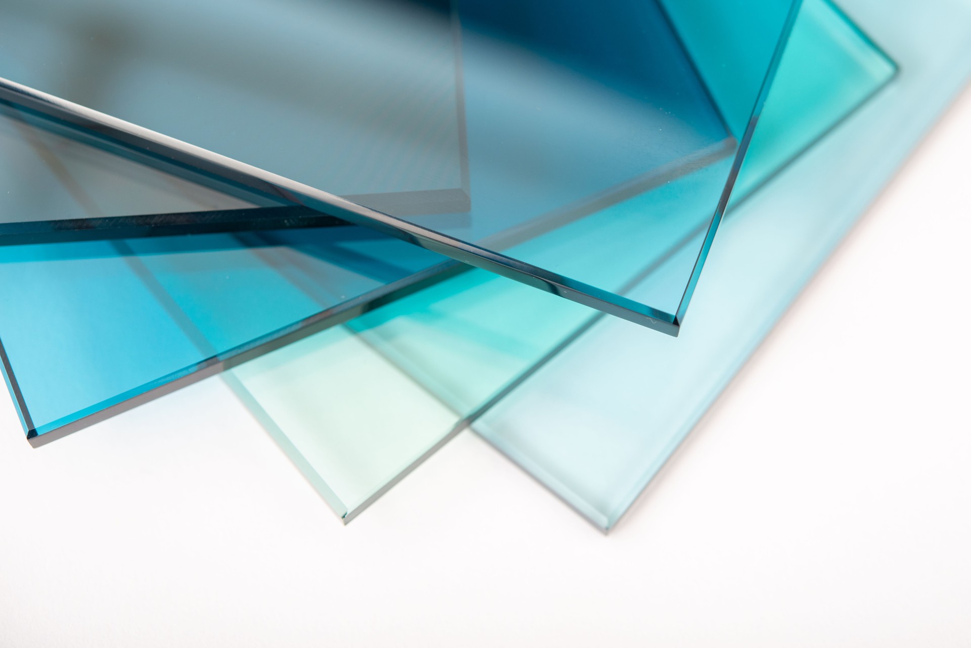 Stacked sheets of 3/8” thick tempered glass in blue-green tones — showcasing the type of premium safety glass used in shower doors.clear float glass panels cut to size