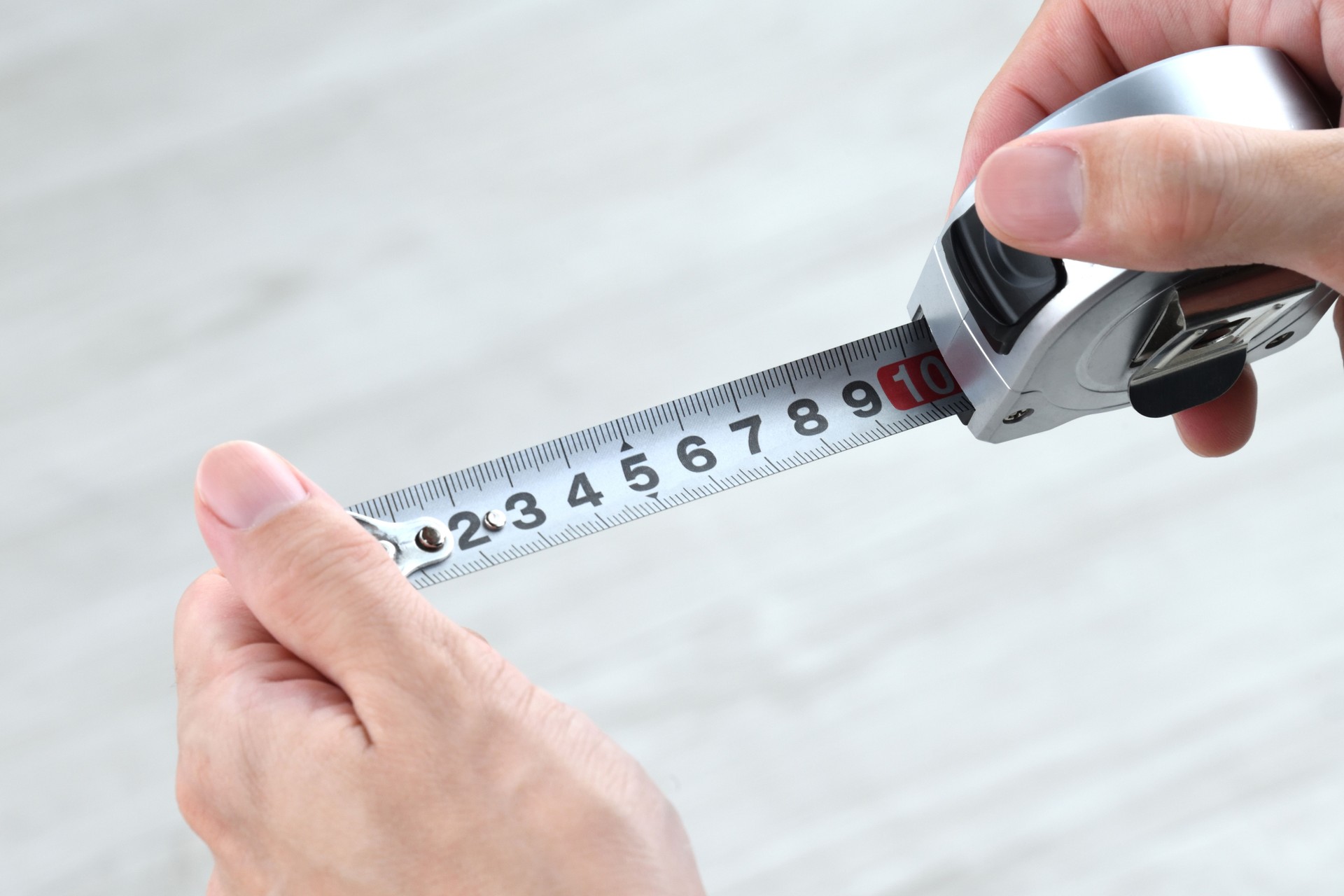 Close-up of a hand using a measuring tape — symbolizing precise on-site measurement service for custom glass installations.