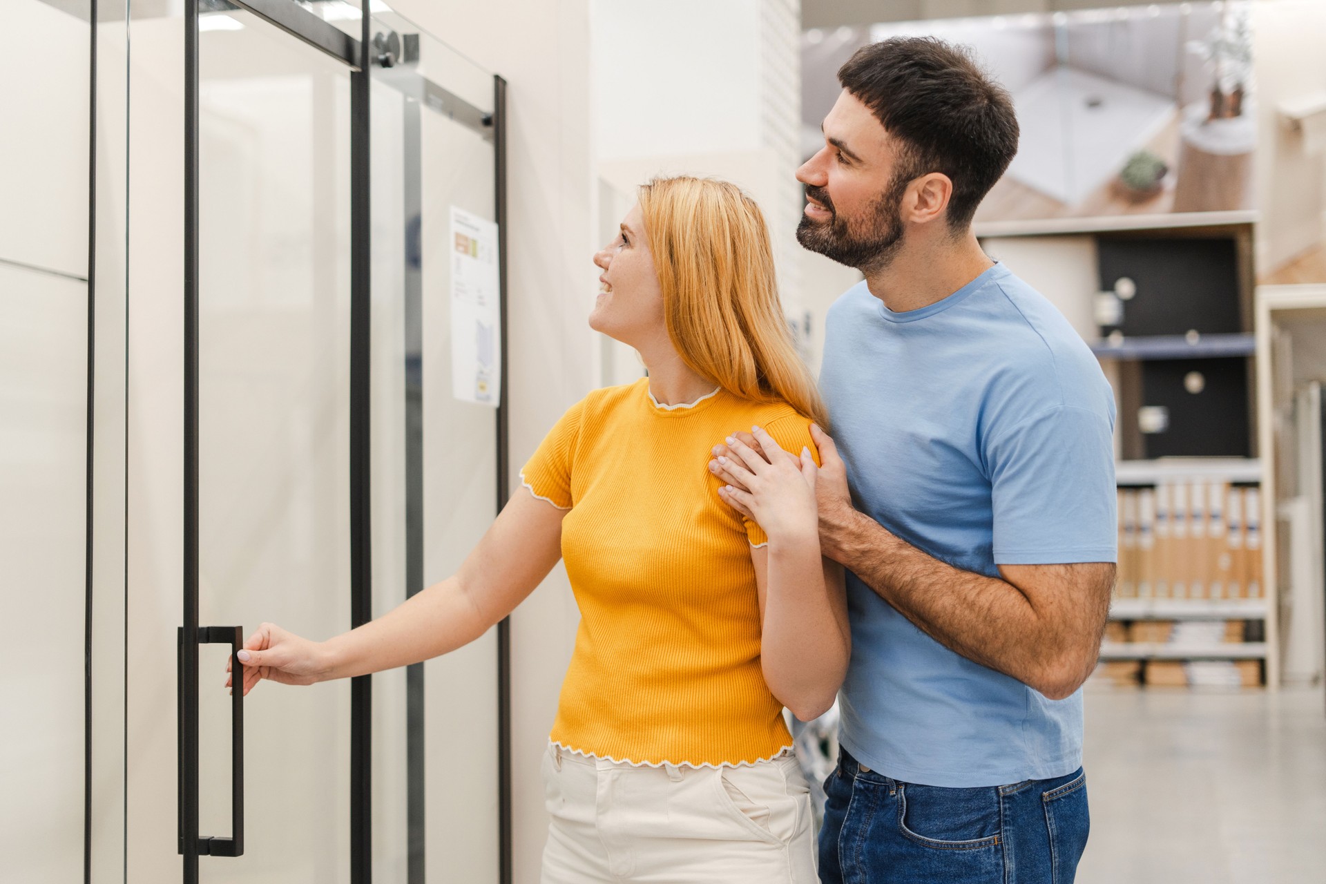 Happy couple admiring new glass shower door at home improvement showroom — reflecting satisfaction and confidence in the finished product.